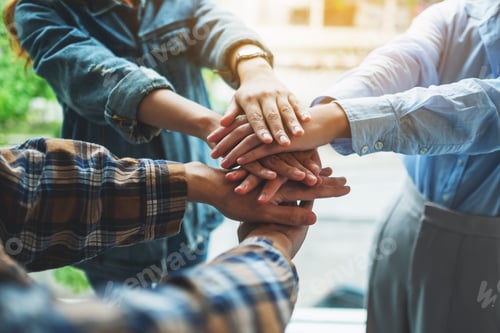Preview: Closeup image of business team standing and joining their hands together in office