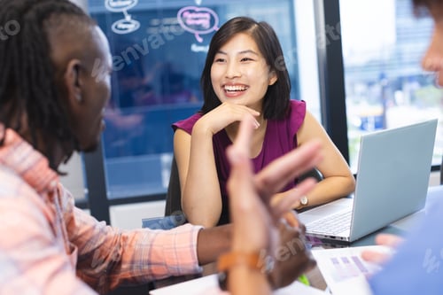 Preview: Diverse team discussing around laptop in a modern business office, Asian woman smiling