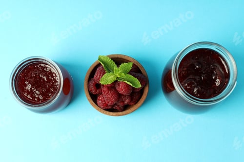 Preview: Jars of raspberry jam with ingredients on blue background