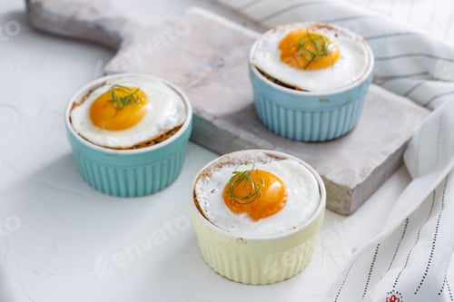 Preview: Three baked egg in ramekins on white background