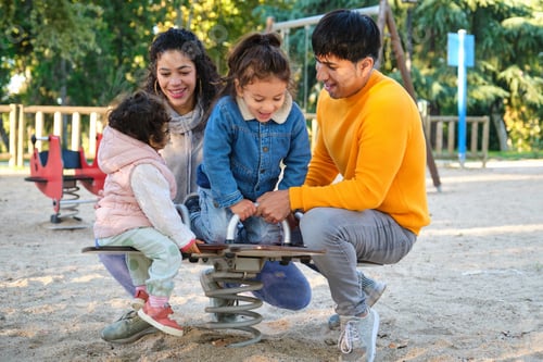 Preview: Hispanic family with two children playing together in a playground.