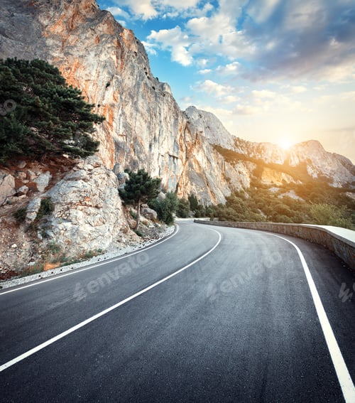 Preview: Winding mountain road with rocks, blue sky at sunset