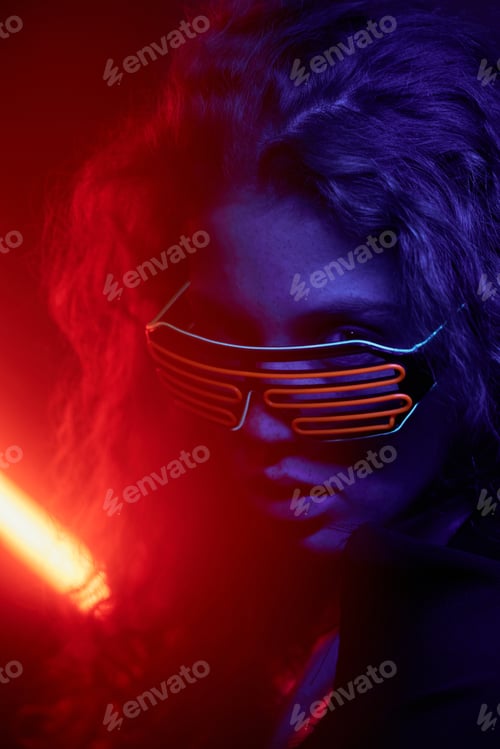 Preview: Confident Young Fashion Model with Curly Hair in Navy Blue and Red Neon Light