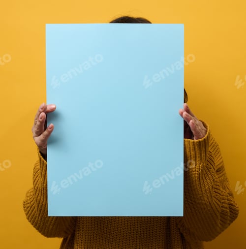 Preview: Woman in an orange sweater holds a blank sheet of paper on a yellow background