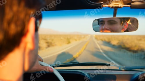 Preview: Male Driver Reflected In Mirror Driving Classic Open Top Car On Road Trip Through Countryside