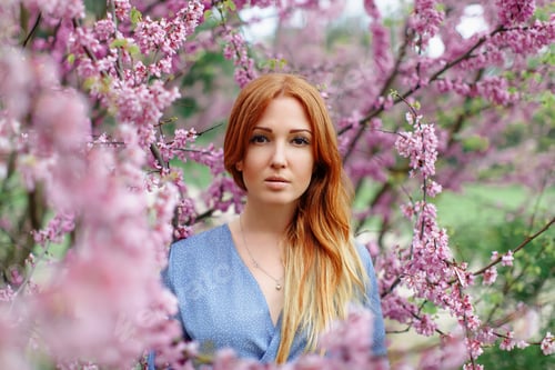 Preview: Beautiful smiling redhead woman in spring time blossom cherrytrees garden