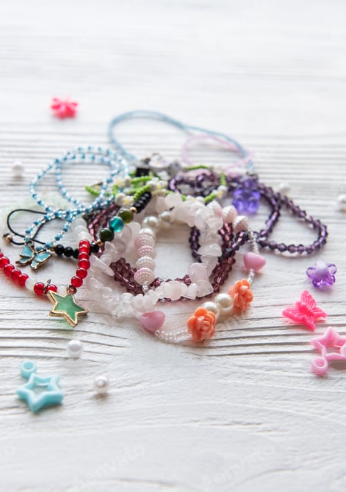 Preview: Colorful handmade jewelry laid out on a wooden surface showcasing various beads and charms