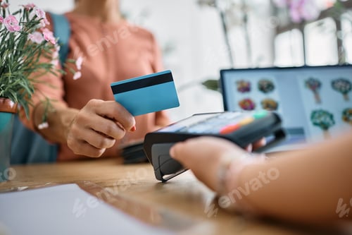 Preview: Close up of woman paying with credit card at flower shop.