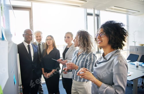 Preview: Diverse group of coworkers strategizing together on an office whiteboard