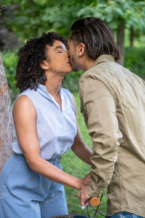 Preview: Interracial couple kissing in park during picnic