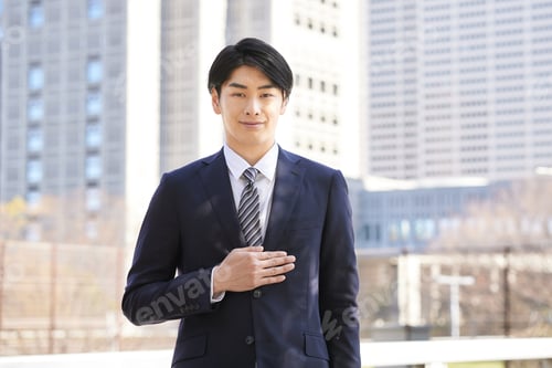 Preview: A Japanese male businessman standing in the background of a building.