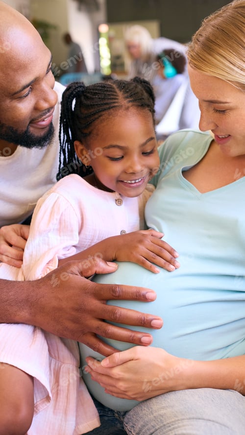 Preview: Family With Daughter Cuddling Pregnant Mother At Home Together