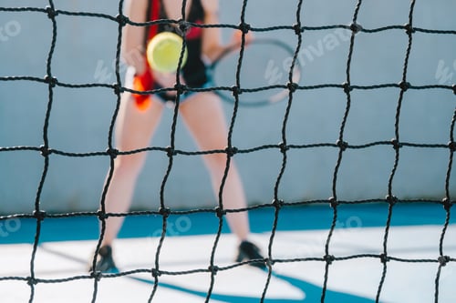 Preview: Young woman playing tennis on the other side of the tennis net