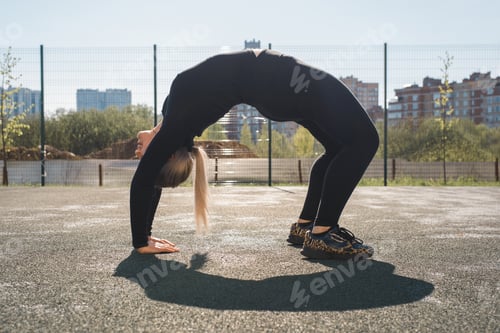Preview: Flexible athlete doing back stretches outdoors. Fitness young woman workout. Training on the outside