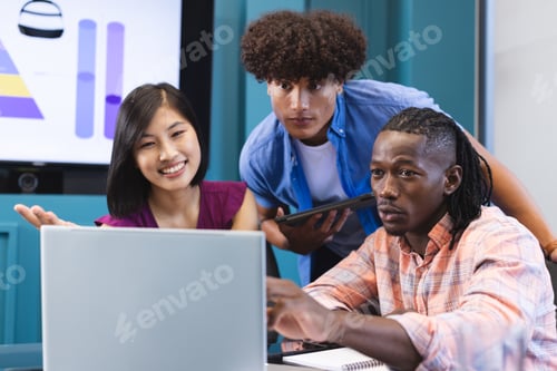 Preview: Diverse group of young colleagues focusing on laptop screen in a modern business office