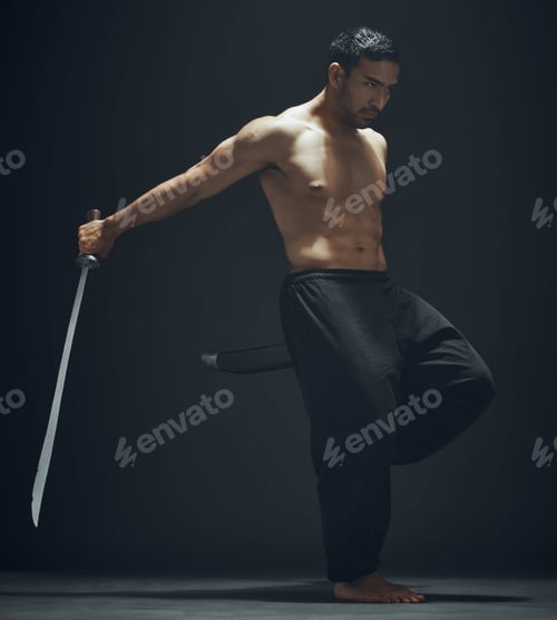 Preview: Full length shot of a handsome young man standing alone in the studio and posing with a broadsword
