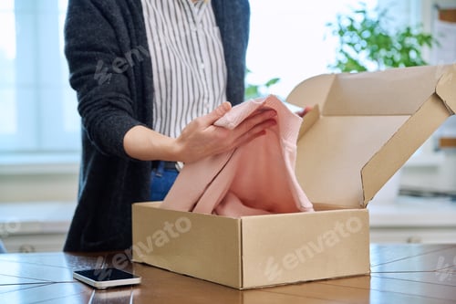 Preview: Close-up of woman's hands unpacking an online purchase from internet clothing store.