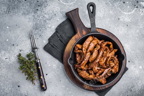 Preview: Delicious glazed teriyaki beef in a skillet. grey background. top view