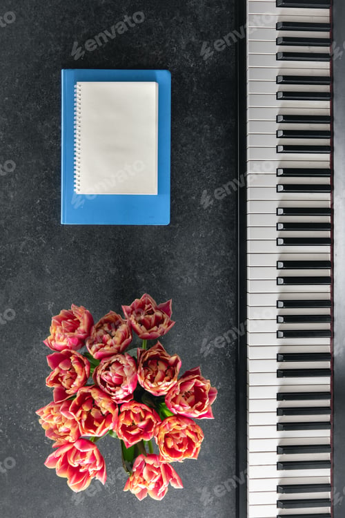 Preview: Piano, bouquet of flowers and notepads on a dark background, top view.