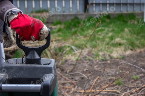 Preview: Work in the garden. Man cutting and crushing branches of trees and berry bushes. Selective focus