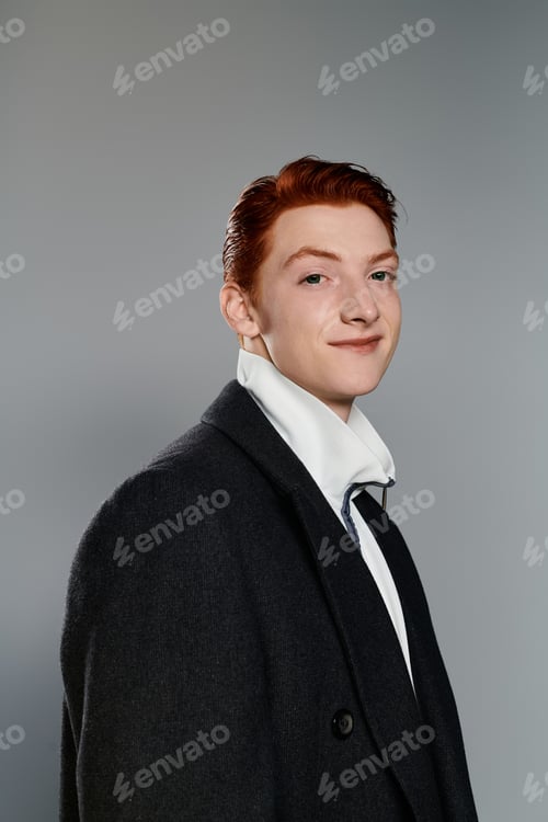 Preview: A stylish man with red hair models winter fashion on a grey backdrop