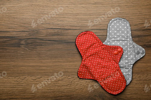 Preview: Reusable cloth menstrual pads on wooden table, flat lay. Space for text