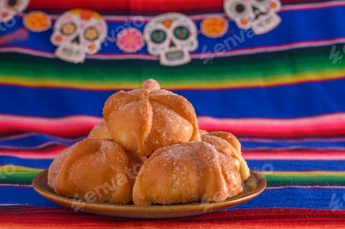 Preview: Pan de muerto with sugar skull figures on colorful serape. Day of the Dead celebration.