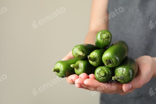 Preview: Woman with ripe green jalapeno peppers on light background, closeup. Space for text