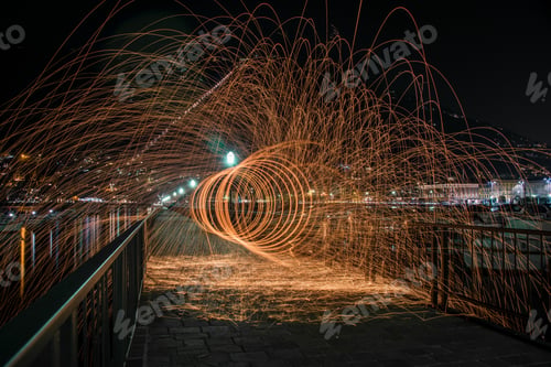 Preview: Horizontal shot of steel wool effect on a bridge with metal railings at nighttime in Como, Italy