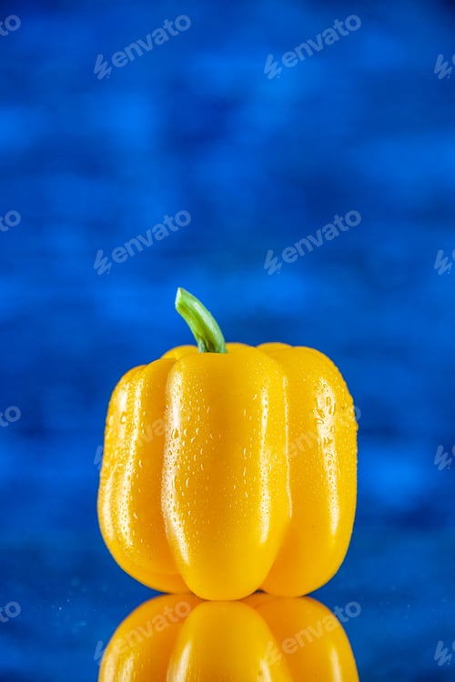 Preview: front view yellow bulgarian pepper with water drops reflection on mirror on blue blurred background