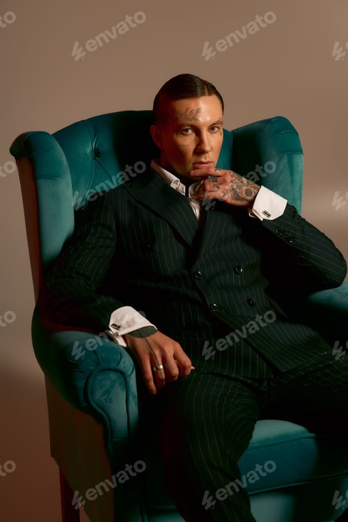 Preview: Timeless elegance of a handsome man in a striking suit sitting in a vintage chair