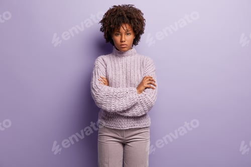 Preview: Serious African American woman looks with self assured facial expression, keeps arms crossed over ch