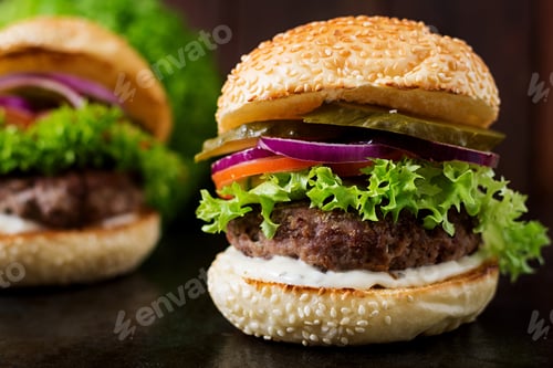 Preview: Big sandwich - hamburger burger with beef, pickles, tomato and tartar sauce on black background.