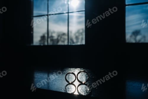 Preview: two gold wedding rings on the windowsill in the sunlight