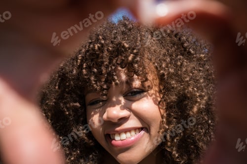 Preview: Close up portrait of smiling young woman with curly hair framing her face