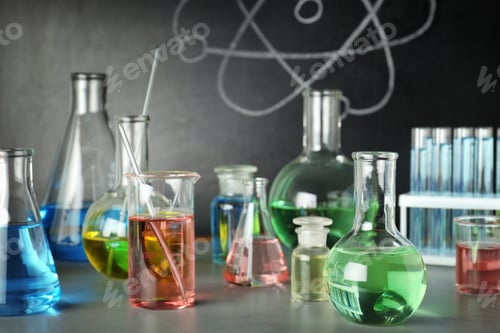 Preview: Laboratory glassware on table near chalkboard. Chemistry concept