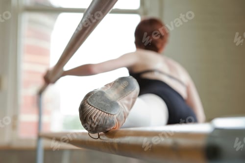 Ballet dancer warming up, foot on bar