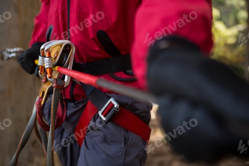 Preview: Man harness tied along with zip line in the forest on a sunny day