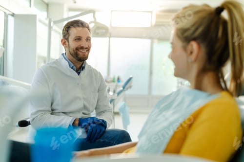 Preview: Handsome man dentist talking with his pretty patient.