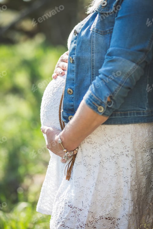 Preview: Pregnant woman holding her belly, close up