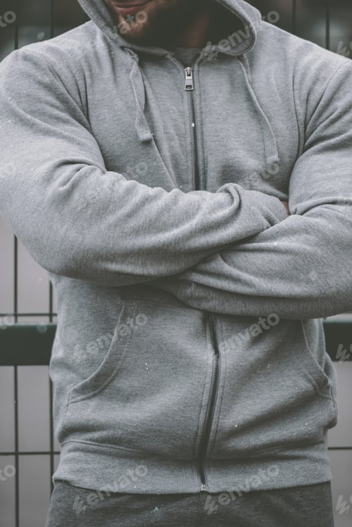 Preview: cropped image of sportsman standing with crossed hands near fence at sports ground
