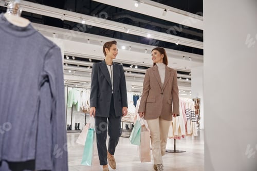 Preview: Young woman friends enjoying shopping together in big fashion shop mall