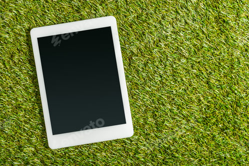 Preview: top view of digital tablet with blank screen on green grass, energy efficiency concept