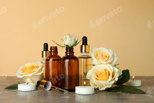 Preview: Bottles with rose essential oil, roses and candles against beige background