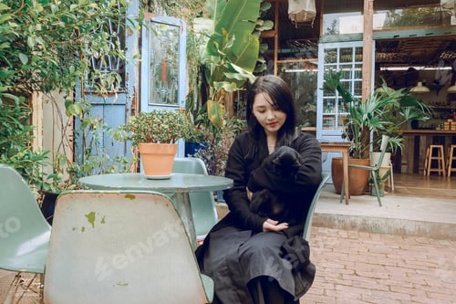 Preview: Woman Holding a Black Dog in Outdoor Cafe