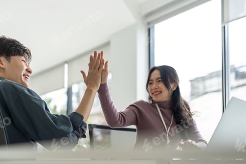 Preview: Successful business people giving each other a high five in a meeting. Two young business