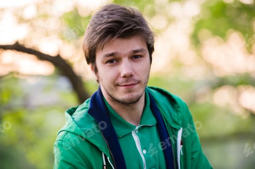 Preview: Young man walking around city listening to music with ear headphones looks at the camera in
