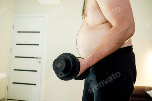 Preview: close up of fat man lifting dumbbell weights sitting at home.