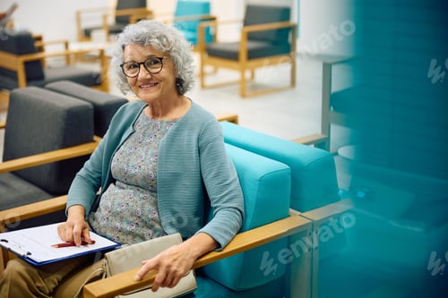Preview: Happy senior woman waiting for doctor's appointment at medical clinic and looking at camera.