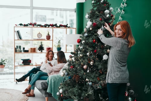 Preview: Feel like a kid again. Portrait of an attractive woman decorating a Christmas tree at home.